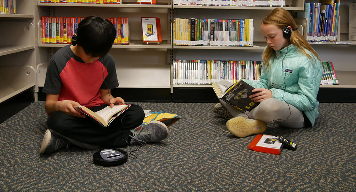 Zander Chao and Hannah Smith listen to books while they read.