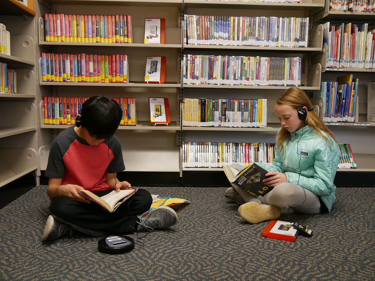 Fourth graders Zander Chao and Hannah Smith listen to books as they read.