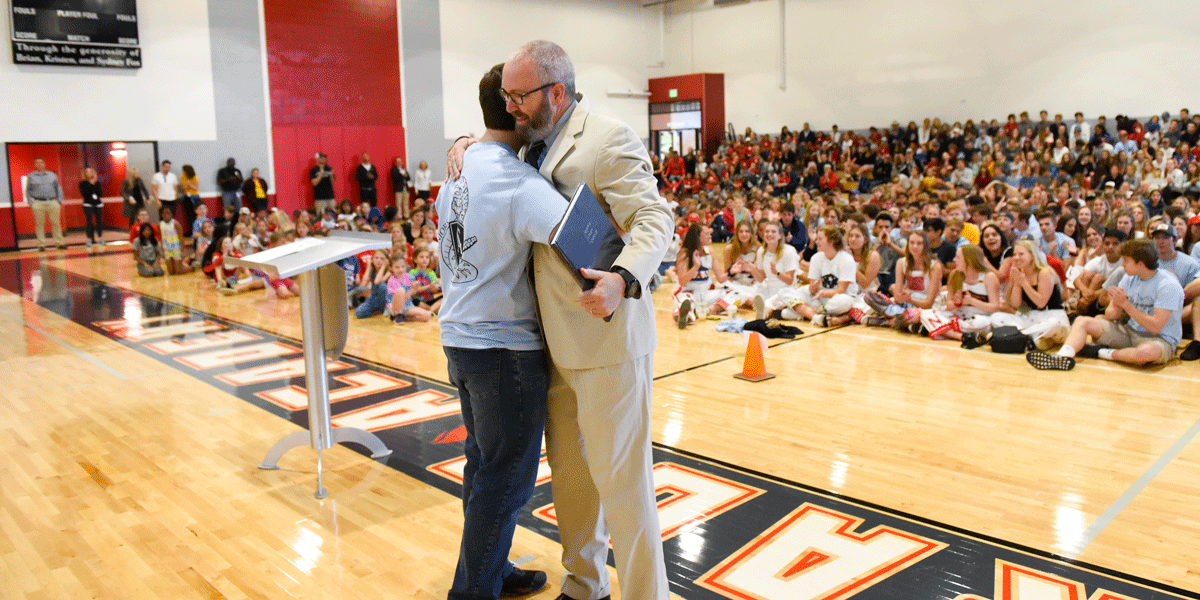 Yearbook Editor Emilio Teran congratulates English teacher Stuart Mills on having the yearbook dedicated to him.